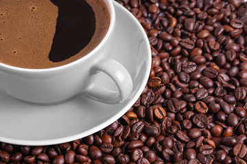 Coffee in gray cup on a table surrounded by coffee beans.