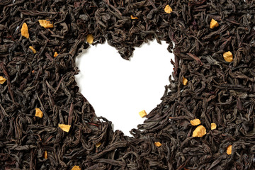 Heart shaped from black tea with passion fruit pieces on white background. Top view. Close up. High resolution