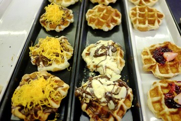 In selective focus waffles with many kinds topping in a tray and selling in whole foods market at night