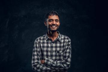 Cheerful hindu guy posing and laughing crossed his arms in the studio on a black background