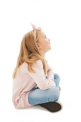 Beautiful little girl sitting on floor, looking on copy space. Isolated on white background