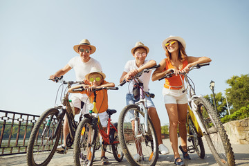 Cheerful family with bicycles standing on embankment