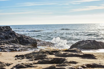 A small wave throughs up spray as it hits the dark rocks that line the Mediterranean coast of southern Spain