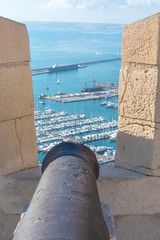 A rusty old canon points out towards the Mediterranean taking aim at the modern marina and the city below