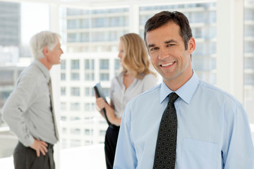 Corporate executive businessman portrait - business partners talking in background