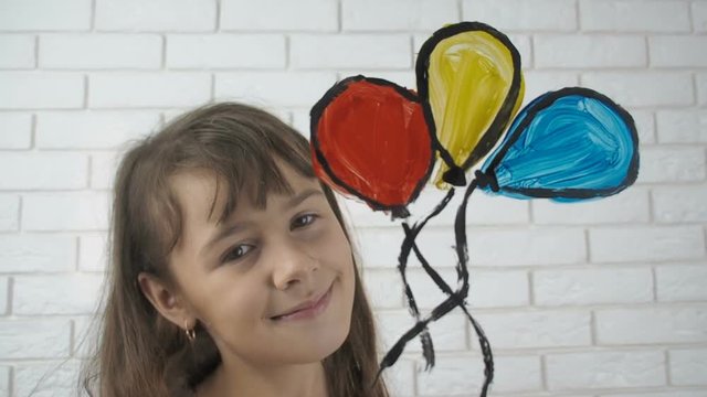 Schoolgirl draws balloons and kite. Cute little one with painted colorful balloons.