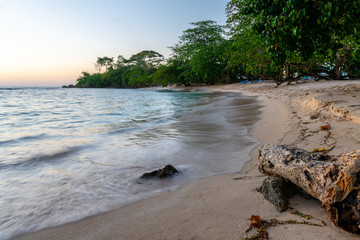Tropical beach vacation setting. Beautiful clear waters on white sand beach.  Subtle sunset in background.