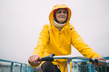 Young woman riding bicycle and wearing raincoat
