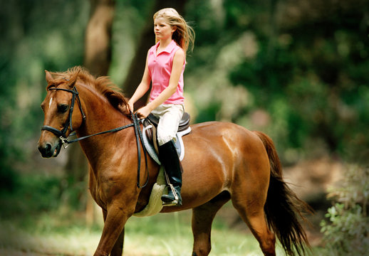 Teenage girl riding a horse outside.