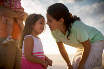 A small girl is about to kiss her mother on a sunny day.