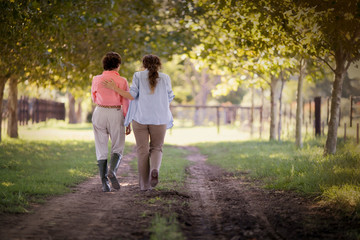 Rear view of two women walking in a field.
