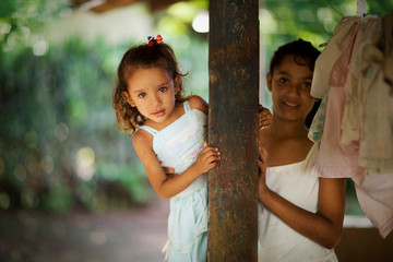 View of two girls holding a pillar.