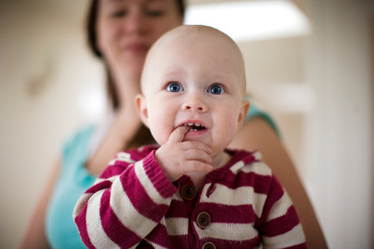 Portrait of a young baby with a finger in his mouth.