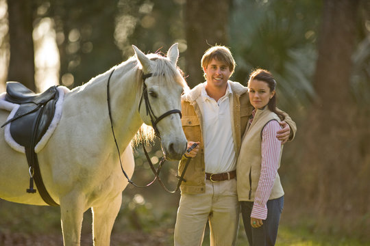 Young couple standing with horse