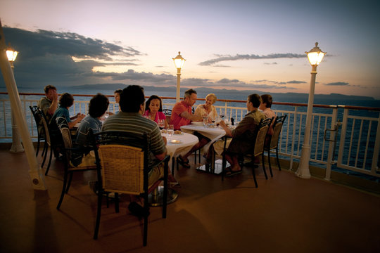 People enjoying a meal on a boat deck at dusk.