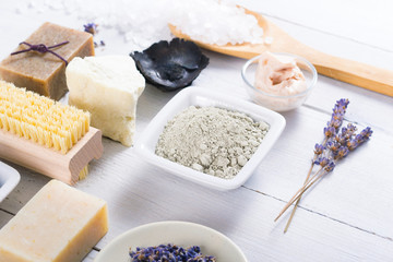 spa massage mud and clay powder, soaps, bath salt, shea butter and lavenders on white wood table background