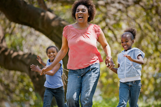 Happy mature woman running hand in hand with her two granddaughters.