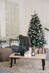 Classic living room interior with a Christmas tree decorated with white balls. New Year's gifts in packaging