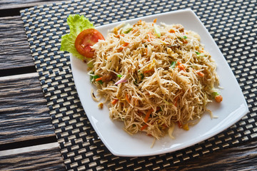 Plate with noodles on a wooden background. View from above.
