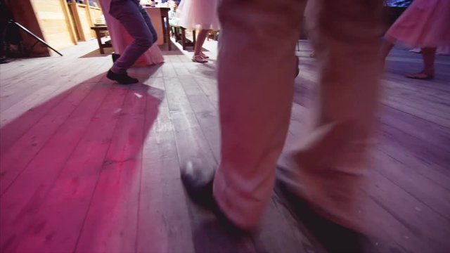 Guests' feet who are dancing and having fun at the wedding. Wooden floor