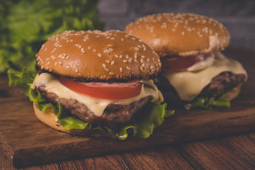 Нamburger or sandwich on brown paper. Delicious sandwich hamburger with meat, cheese and fresh vegetable. Hamburger or sandwich is the popular fast food for brunch or lunch. Juicy cheeseburger