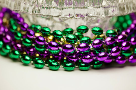 Macro abstract art image of traditional three color Mardi Gras beads in a frosted lead crystal bowl