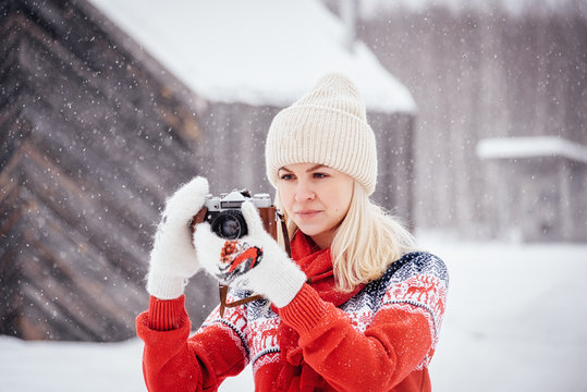 Nikola-Lenivets, Russia - January 26, 2019: Beautiful girl in a red sweater with a vintage camera