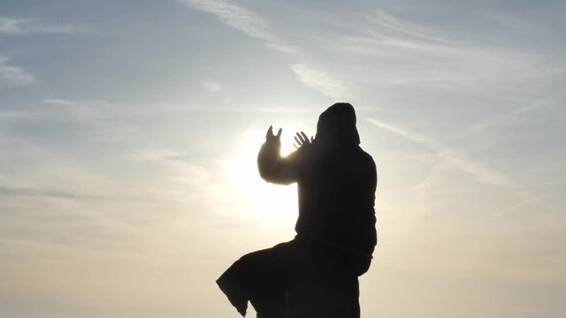 sitting Prayer in ancient black hoodie silhouette with sky background