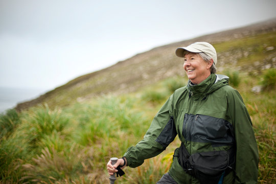 Woman smiles as she stops to admire the scenery on a hike.