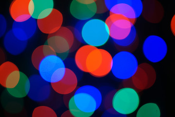 Multi-color blue holiday garland. Garland is blurred. Many big colorful round lights. Fully defocused photo. Blurred background and foreground. Holiday mood. New Year and Christmas is coming.