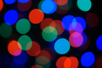 Multi-color blue holiday garland. Garland is blurred. Many big colorful round lights. Fully defocused photo. Blurred background and foreground. Holiday mood. New Year and Christmas is coming.