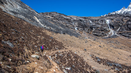 Landscape view of one female alpinist standing on the track leading to Kongma La pass.  Sagarmatha (Everest) National Park, Nepal.