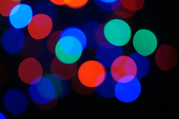 Multi-color blue holiday garland. Garland is blurred. Many big colorful round lights. Fully defocused photo. Blurred background and foreground. Holiday mood. New Year and Christmas is coming.