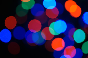 Multi-color blue holiday garland. Garland is blurred. Many big colorful round lights. Fully defocused photo. Blurred background and foreground. Holiday mood. New Year and Christmas is coming.