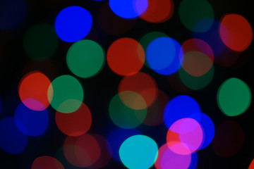 Multi-color blue holiday garland. Garland is blurred. Many big colorful round lights. Fully defocused photo. Blurred background and foreground. Holiday mood. New Year and Christmas is coming.
