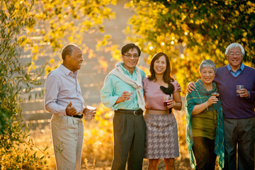 Smiling group of friends celebrating with drinks in a back yard.