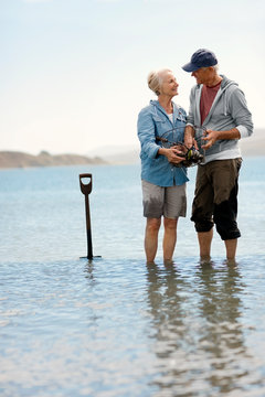 Smiling senior couple standing on a beach together.