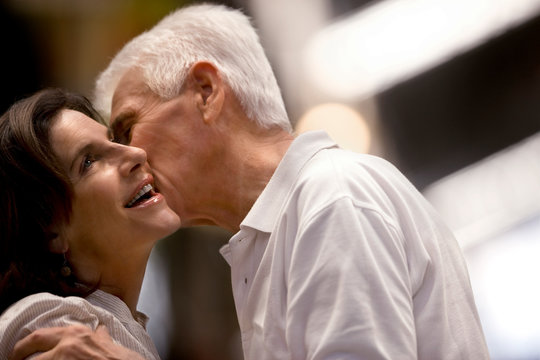 Middle-aged man kissing his wife on the cheek.