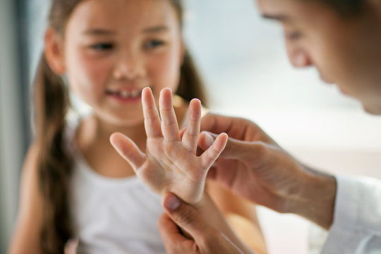 Doctor examining the hands of a young patient.