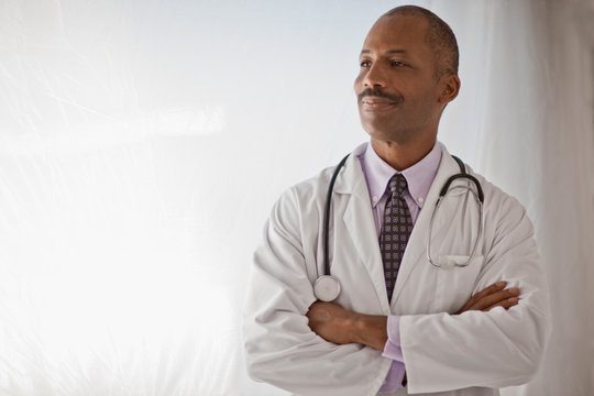 Male doctor with his arms crossed smiling in pride.