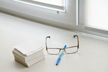 Note sheets, glasses and a pen lie on the windowsill in the office