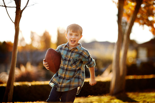 Portrait of running boy holding his rugby ball in the backyard.