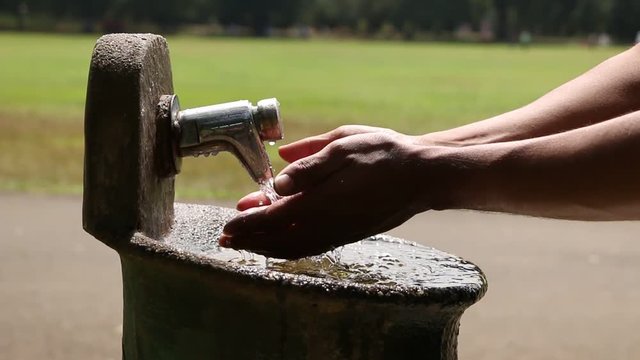 Someone drinking water from a garden fountain tap , A full 1080p footage