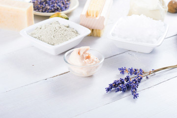 spa products: black mud and clay powder, cosmetic cream, soap, bath salt, shea butter and lavenders on white wood table background