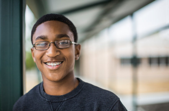 Portrait of smiling teenage boy wearing eyeglasses standing in school