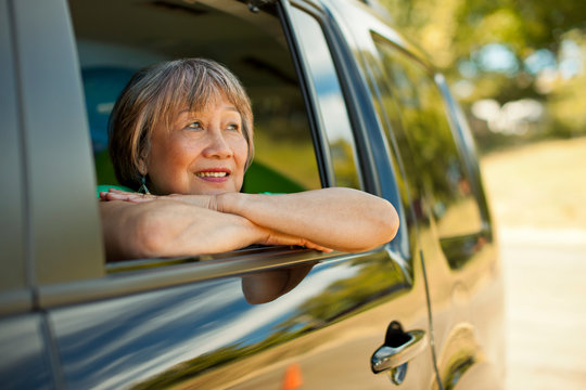 Happy senior woman looking out the window of a SUV.