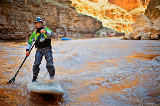 Mid adult man paddleboarding on a river.