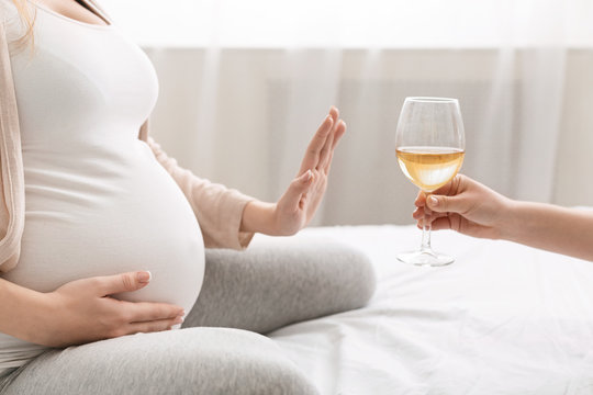 Young pregnant woman refuses to drink wine