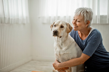 Portrait of a happy mature woman hugging her pet Labrador.