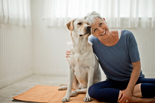 Smiling mature woman with dog sitting indoors